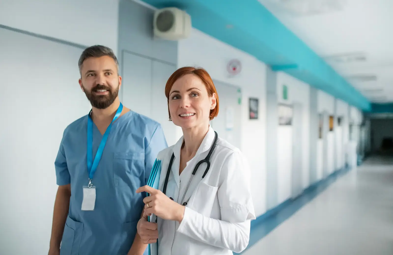 Infirmier et infirmière souriants dans un couloir d'hôpital